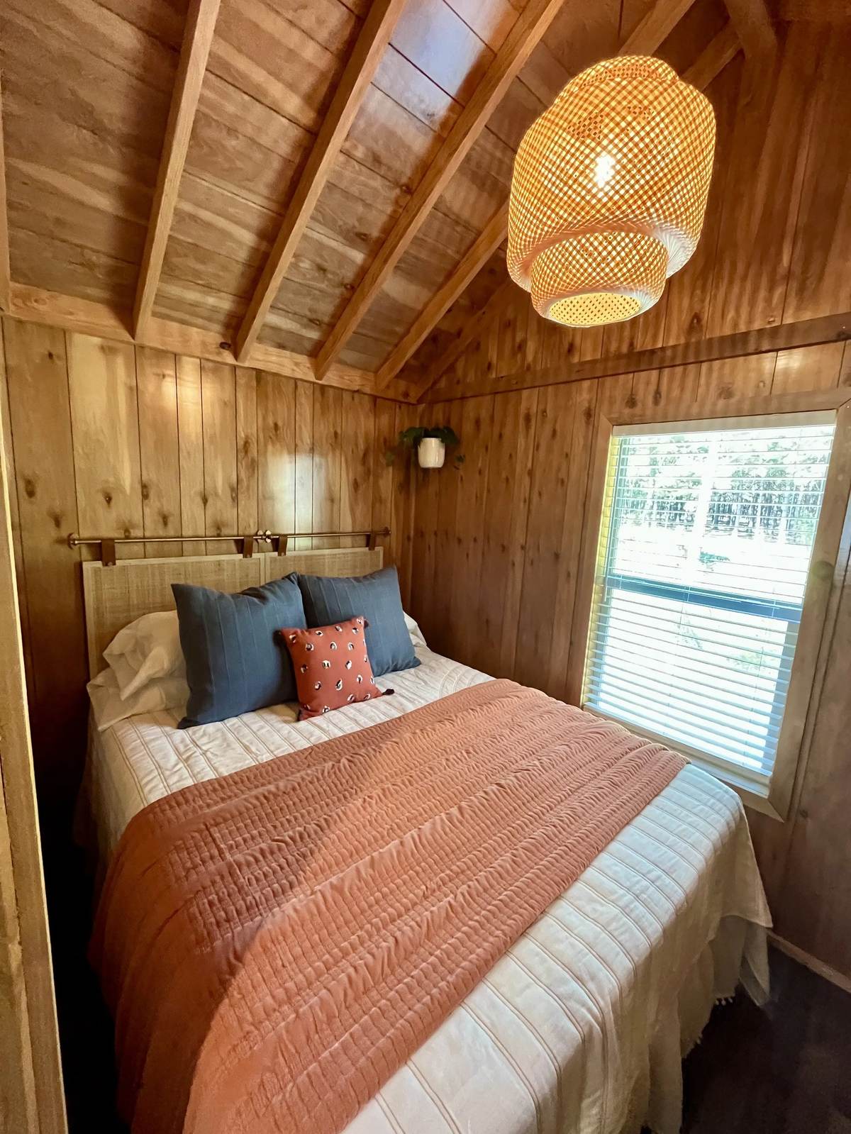 Inside a cedar-lined cabin with a vaulted ceiling and woven pendant light