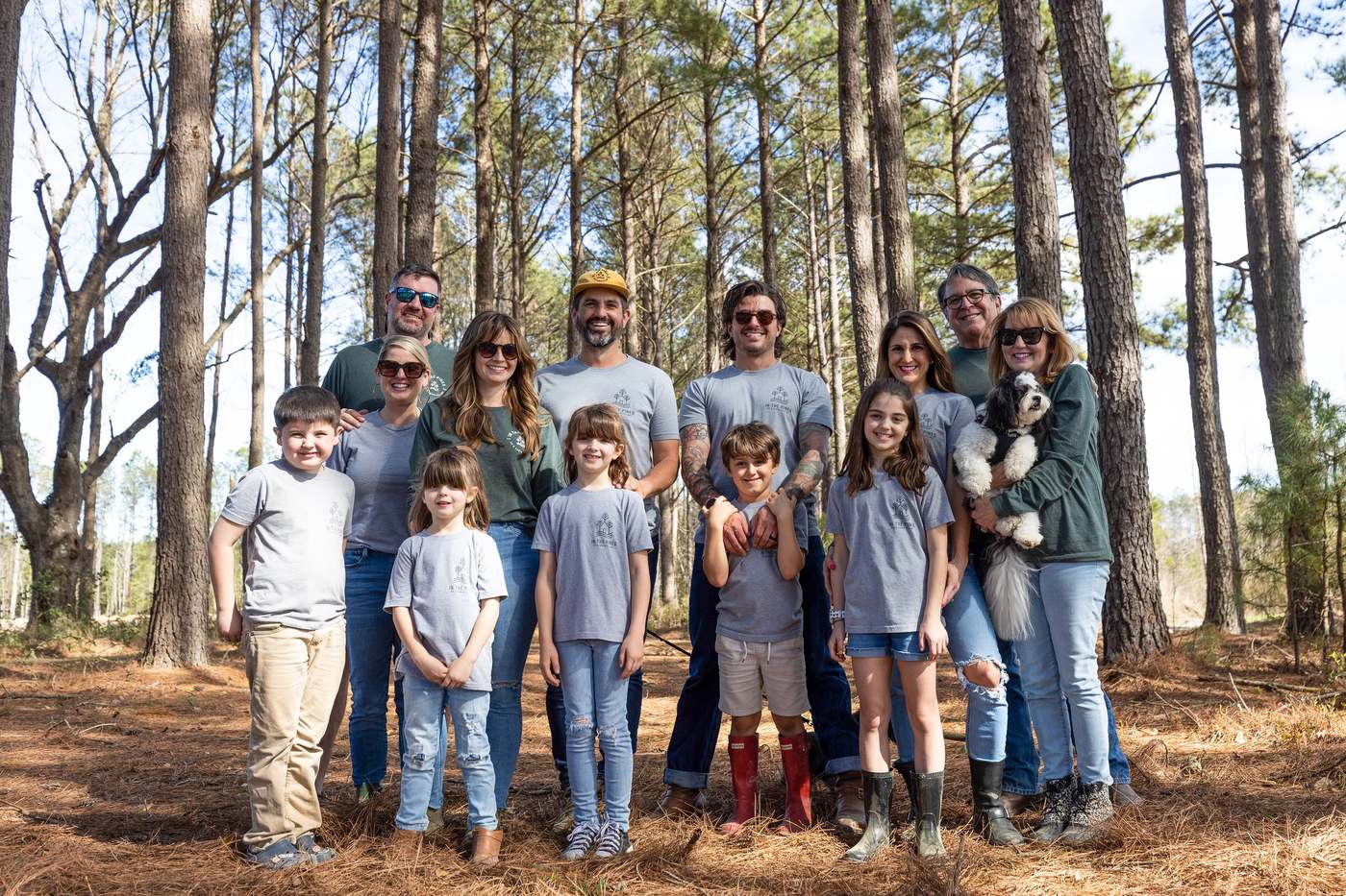 The Judge family standing together among the pine trunks at the campground
